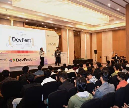 Speakers on the DevFest Lucknow 2025 stage facing a seated audience
